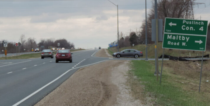 slide1 Road with vehicles and a green sign showing directions to Puslinch Concession 4 and Maltby Road West.