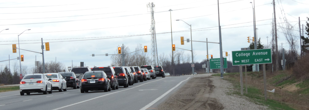 slide5 Line of cars stopped at a red light on a multi-lane road with a green sign for College Avenue, indicating West (left) and East (right).